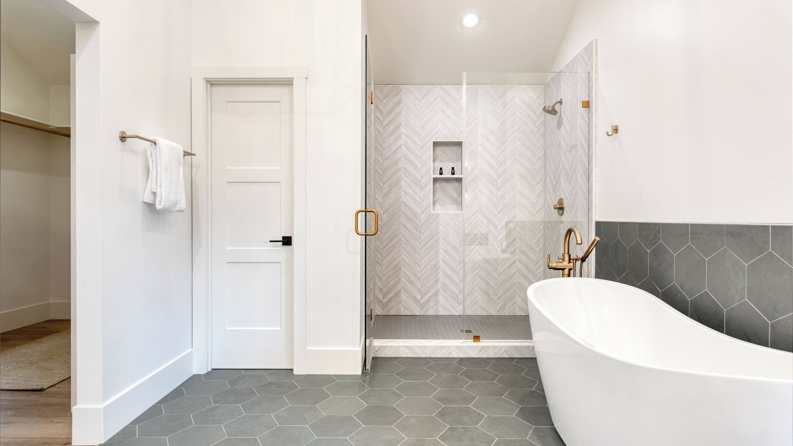 A modern bathroom with a freestanding bathtub, a shower enclosure, and a white door.