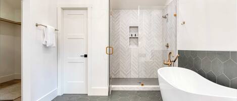 Un baño moderno con una bañera independiente, zona de ducha y puerta que da a otra habitación.
