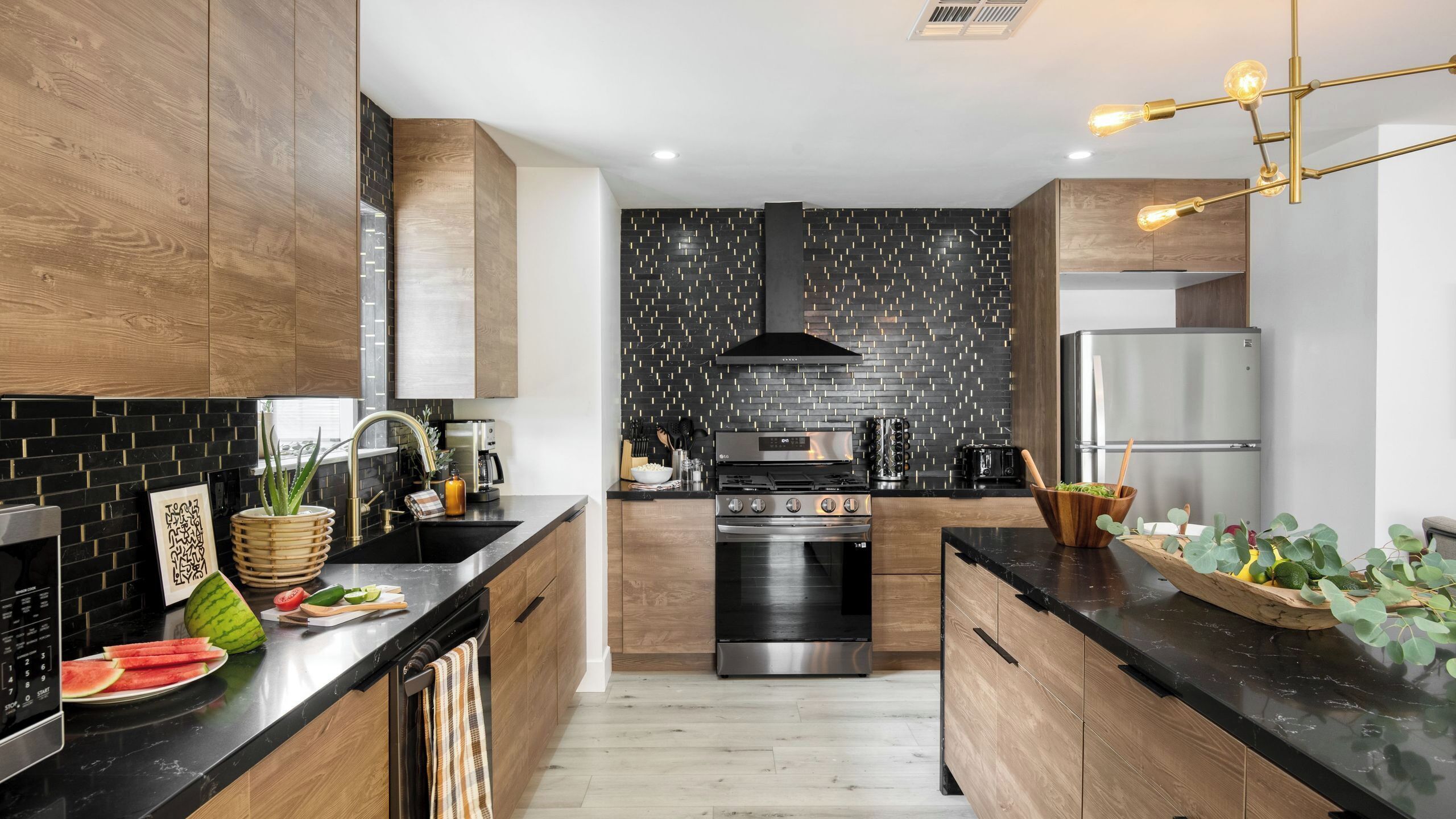 A modern kitchen with wooden cabinets, a black backsplash, stainless steel appliances, and a central island.