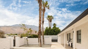 A modern building with a white exterior, a paved courtyard, and tall palm trees. - Yellowjacket by Avantstay Entertainers Yard 10min to Downtown (Palm Springs)