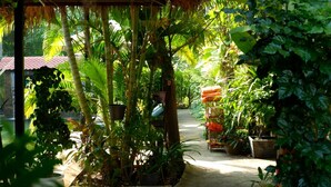 A covered outdoor area with a thatched roof, surrounded by lush greenery and potted plants. - Nary Villa (Siem Reap)