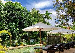 A pool area with lounge chairs and umbrellas, surrounded by lush greenery. - Nary Villa (Siem Reap)