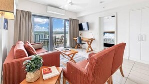 Une chambre d’hôtel moderne équipée d’un canapé, d’un fauteuil, d’une table à manger et d’un téléviseur.