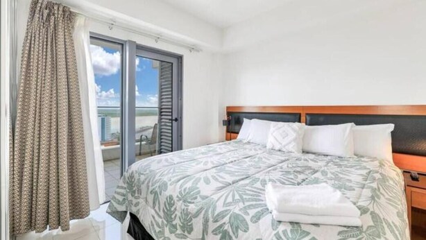 Une chambre d’hôtel avec un lit, une table de chevet, une fenêtre avec des rideaux et une vue sur l’extérieur.
