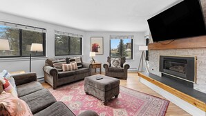 A modern living room with a fireplace, two sofas, a coffee table, and a flat-screen TV. - Plaza #1404 by Summit County Mountain Retreats (Keystone)