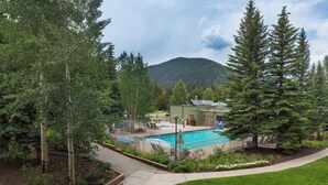 A swimming pool surrounded by a fence, with trees and a mountain in the background. - Plaza #1404 by Summit County Mountain Retreats (Keystone)