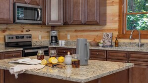 A kitchen with wooden cabinets, a microwave, a coffee maker, and a granite countertop.