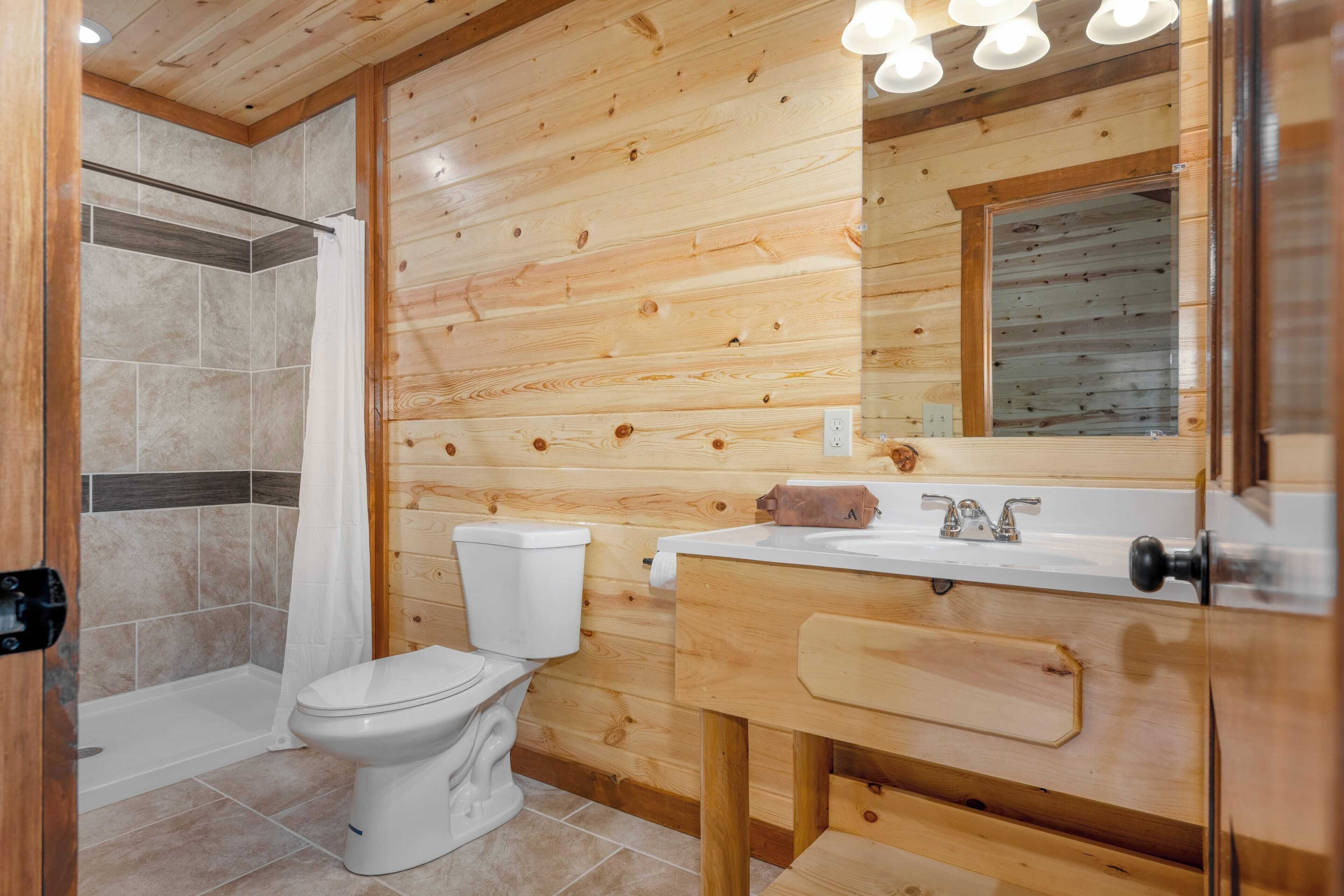 A wooden cabin bathroom with a shower, toilet, and sink.