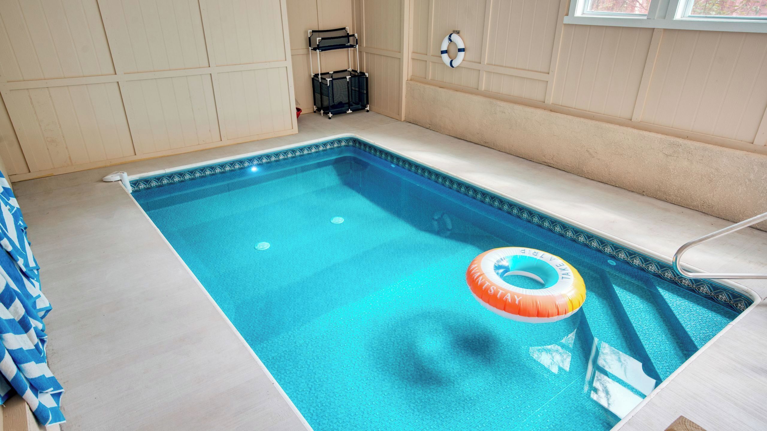 Une piscine avec un bord bleu, un flotteur et un porte-serviettes.