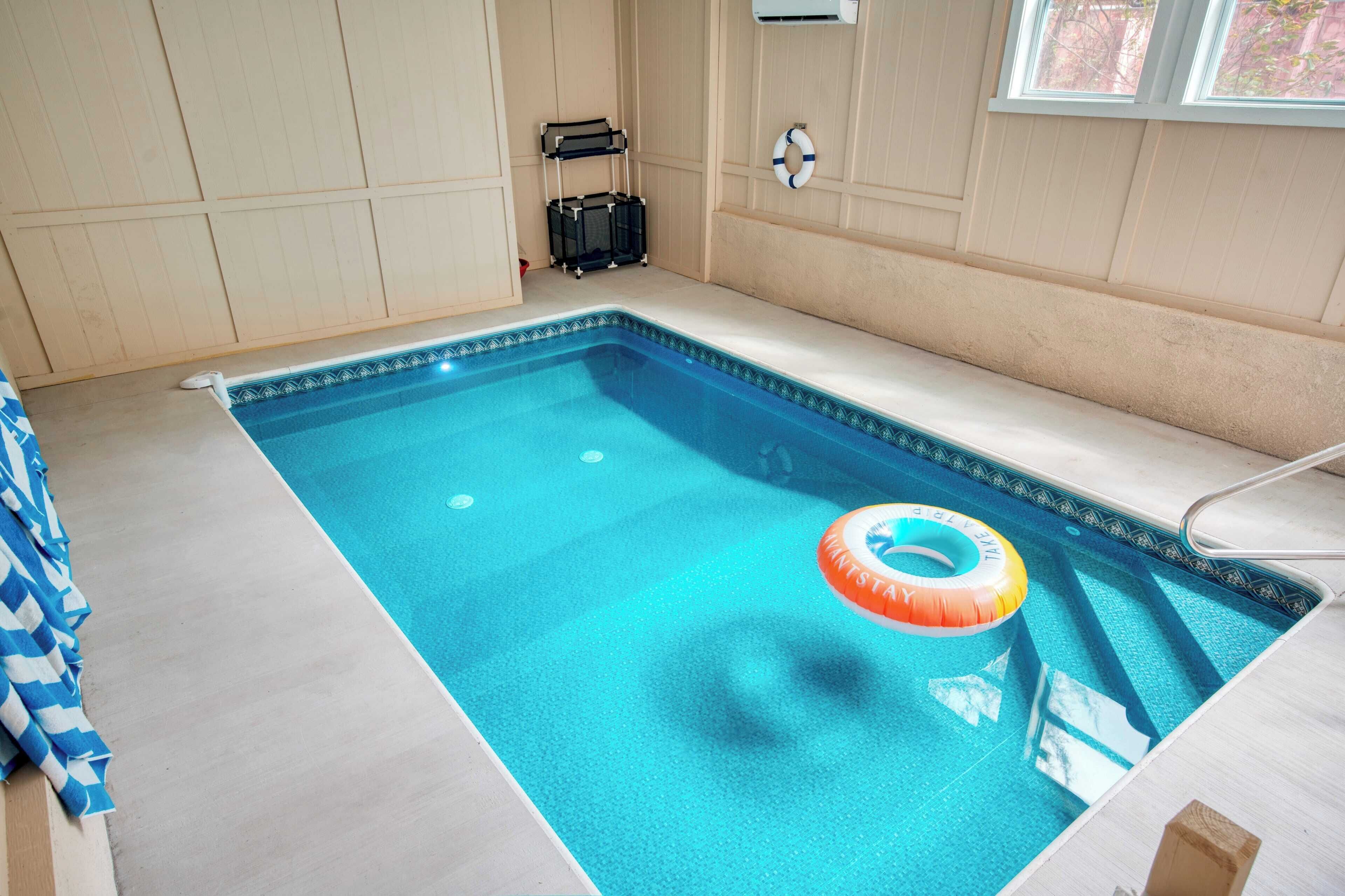 A swimming pool with a lifebuoy, a towel rack, and a suitcase.