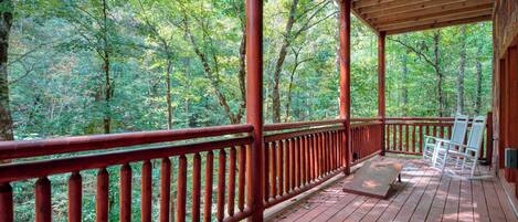 Um deck de madeira com corrimão vermelho, com vista para uma floresta.