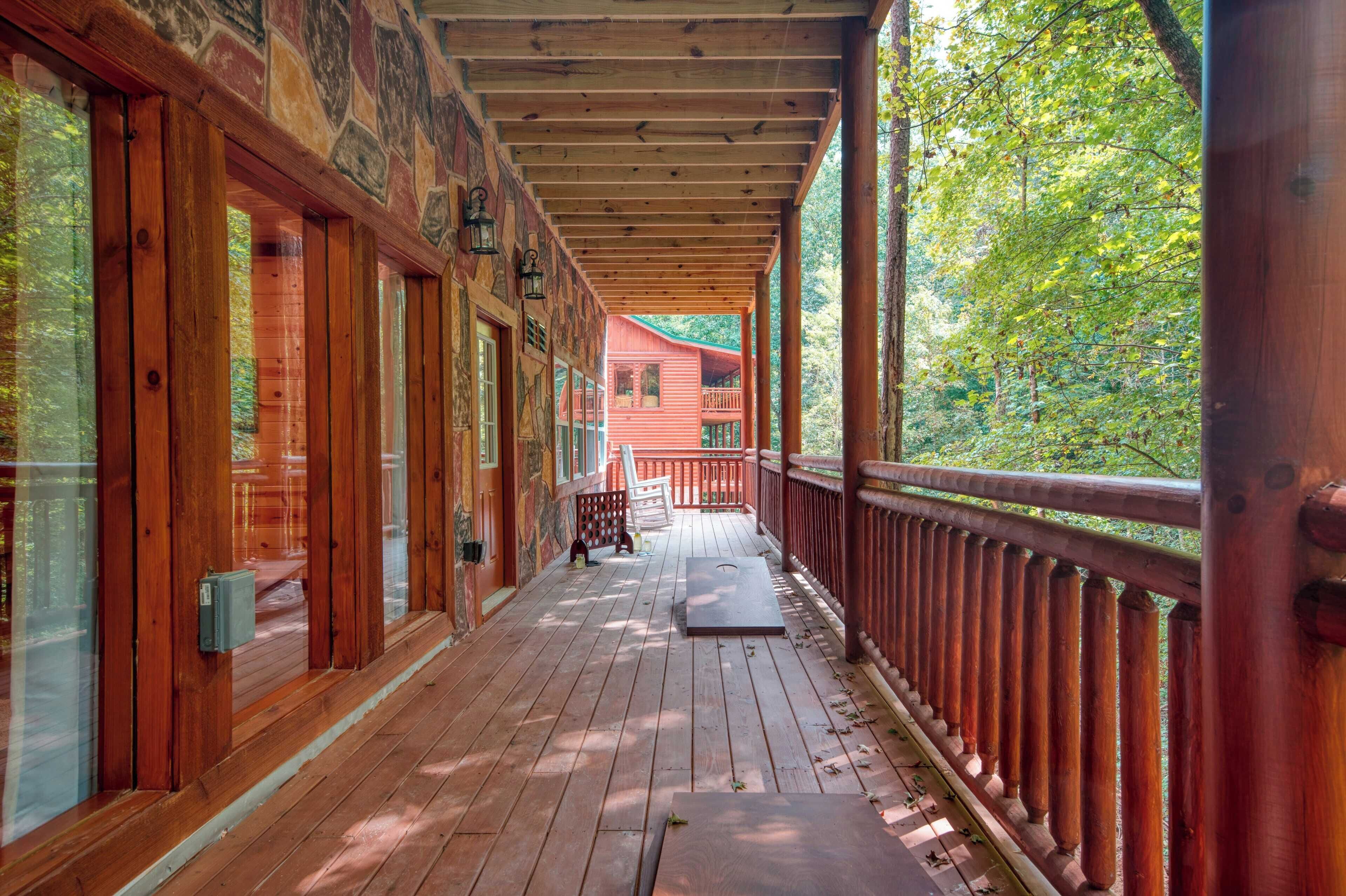 A wooden deck with a covered walkway, wooden railings, and a view of a red building in the distance.