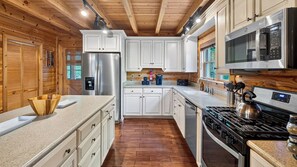 Une cuisine moderne avec des meubles blancs, des appareils en acier inoxydable et un plancher en bois.