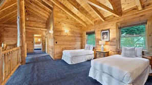 A wooden cabin with two beds, a small table, and a window with a view of greenery. - Leyland by Avantstay Cabin Mansion w/ Views (Asheville)