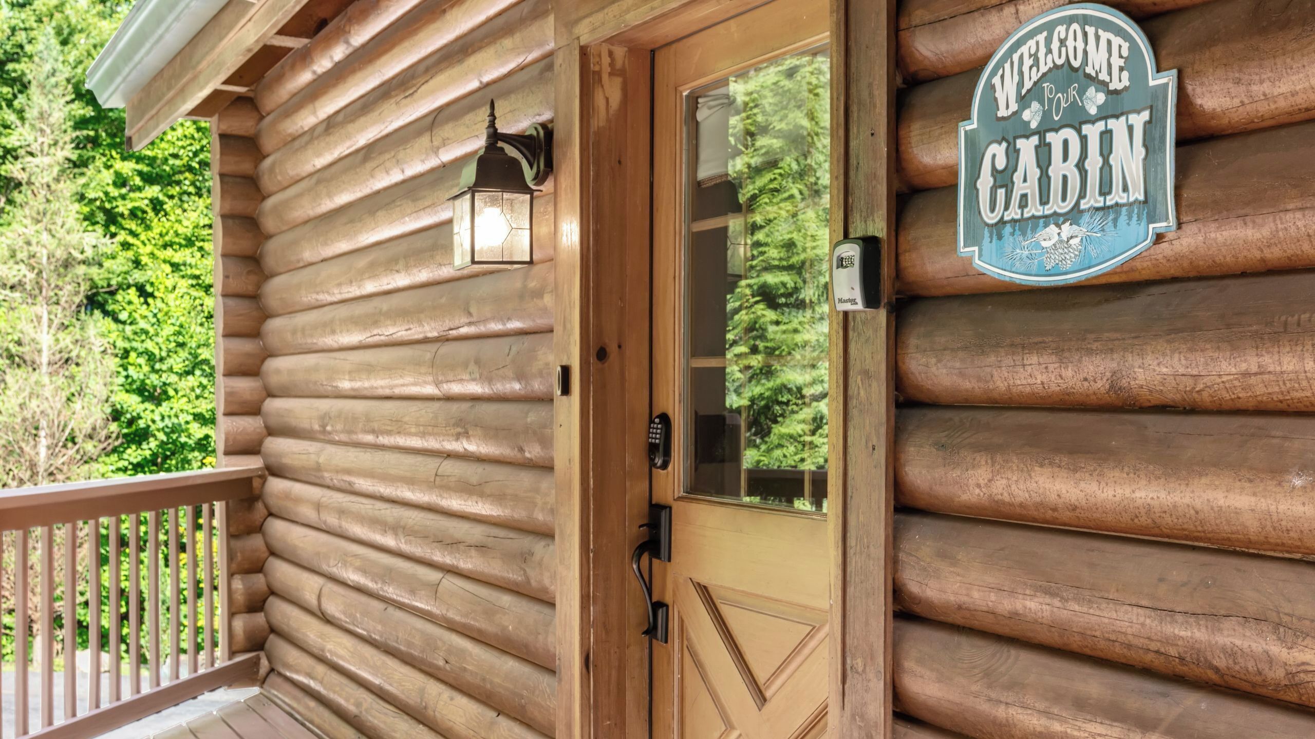 A wooden cabin with a door, a welcome sign, and a mailbox.