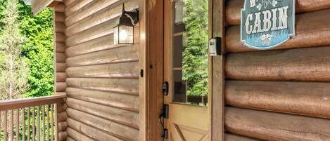 A wooden cabin with a door, a welcome sign, and a mailbox.