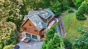 Une cabane en rondins avec des fondations en pierre, un jacuzzi et une terrasse couverte.
