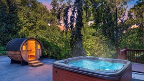 A hot tub and a wooden barrel structure with a bench inside, surrounded by trees. - Leyland by Avantstay Cabin Mansion w/ Views (Asheville)