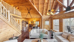 A log cabin interior with a dining area, sofa, and a staircase.