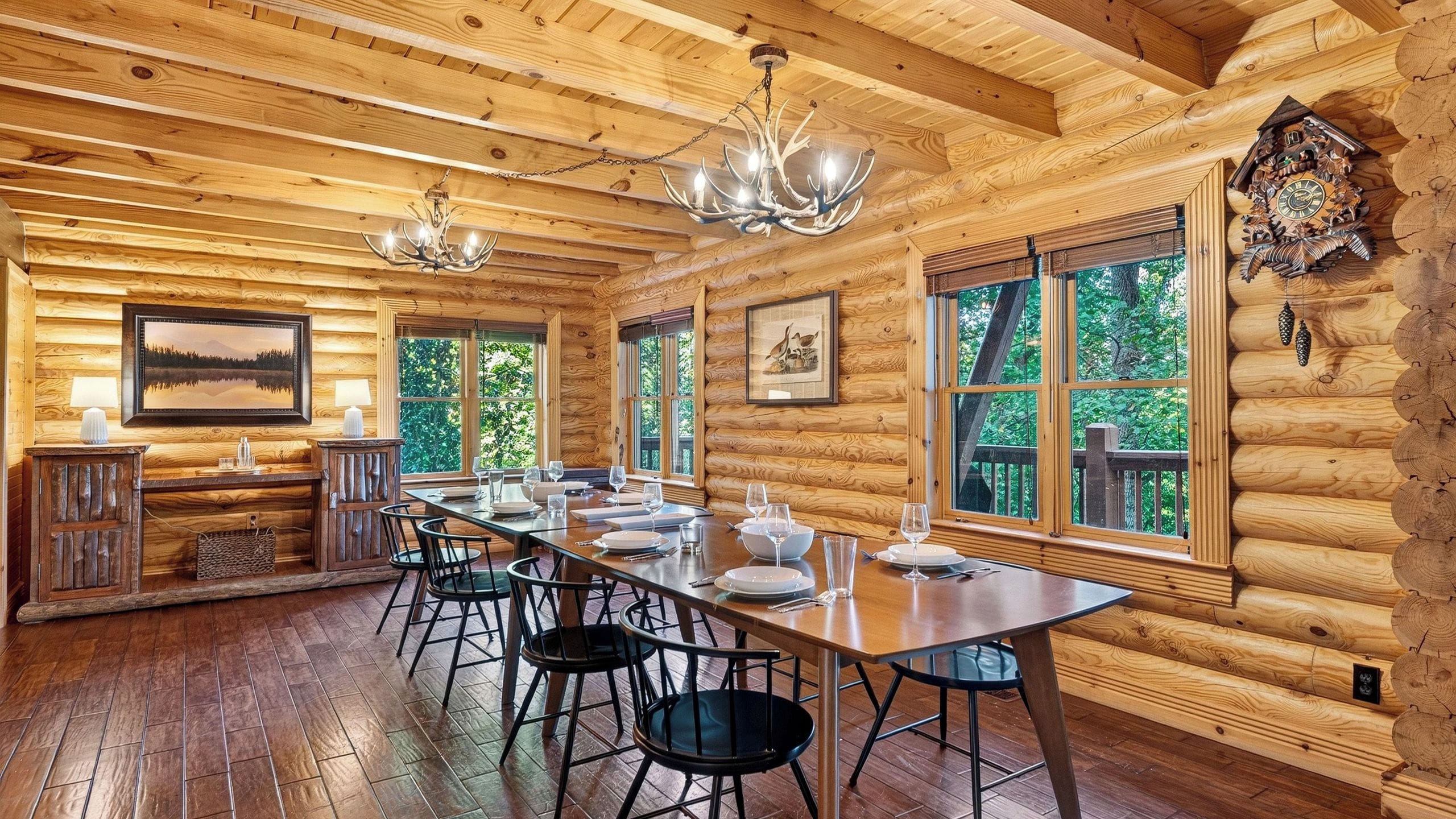 A log cabin interior with a dining area, wooden walls, and large windows.