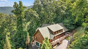 A cabin with a stone foundation, wooden exterior, and a deck.