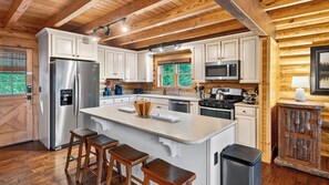 Une cuisine moderne dotée d’un îlot central, d’appareils électroménagers en acier inoxydable et d’un revêtement de sol en bois.