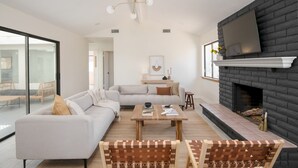 A modern living room with a fireplace, a sofa set, and a coffee table. - Archie by Avantstay Desert Retreat w/ Pool, Edge of Joshua Tree, Bonus Casita for Group Travel (Yucca Valley)