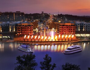 A waterfront hotel with a central fountain, a boat dock, and surrounding buildings. - The LUX @ Stonebridge - Close to SDC - Resort Amenities!! (Branson West)