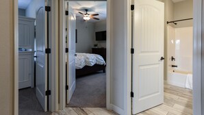 A bedroom with a bed, a ceiling fan, and a bathroom with a bathtub. - The Splendor @ Stonebridge D - Onsite Fishing - Close to SDC (Branson West)