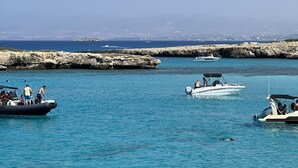 A marina with several boats docked, calm water, and a rocky breakwater in the background. - Pathos Penthouse A Slice of Paradise (Geroskipou)