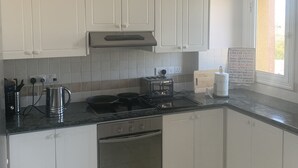 A modern kitchen with white cabinets, a stainless steel stove, and a window providing natural light. - Pathos Penthouse A Slice of Paradise (Geroskipou)