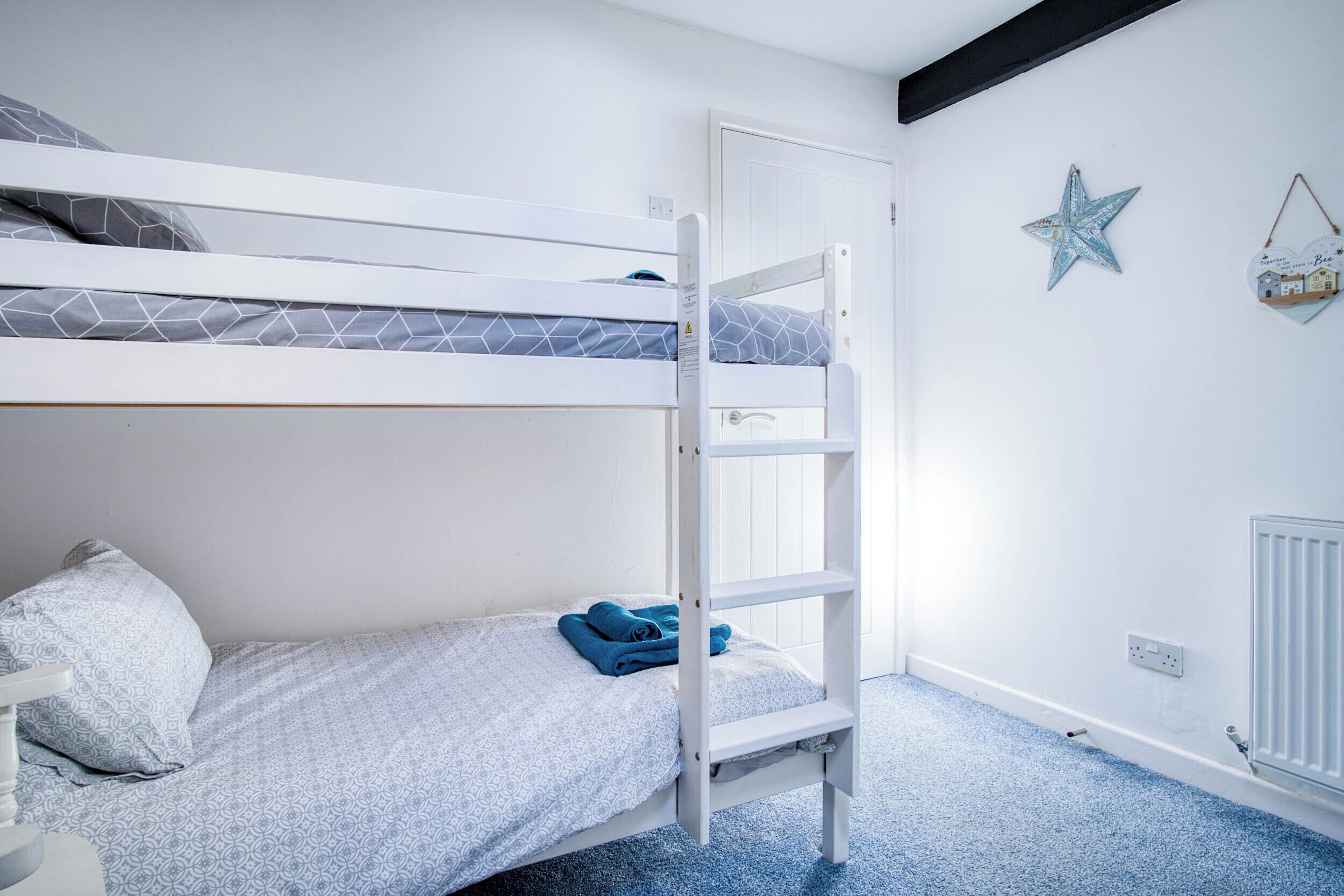 A bunk bed room with a ladder, a white door, and a star decoration on the wall.