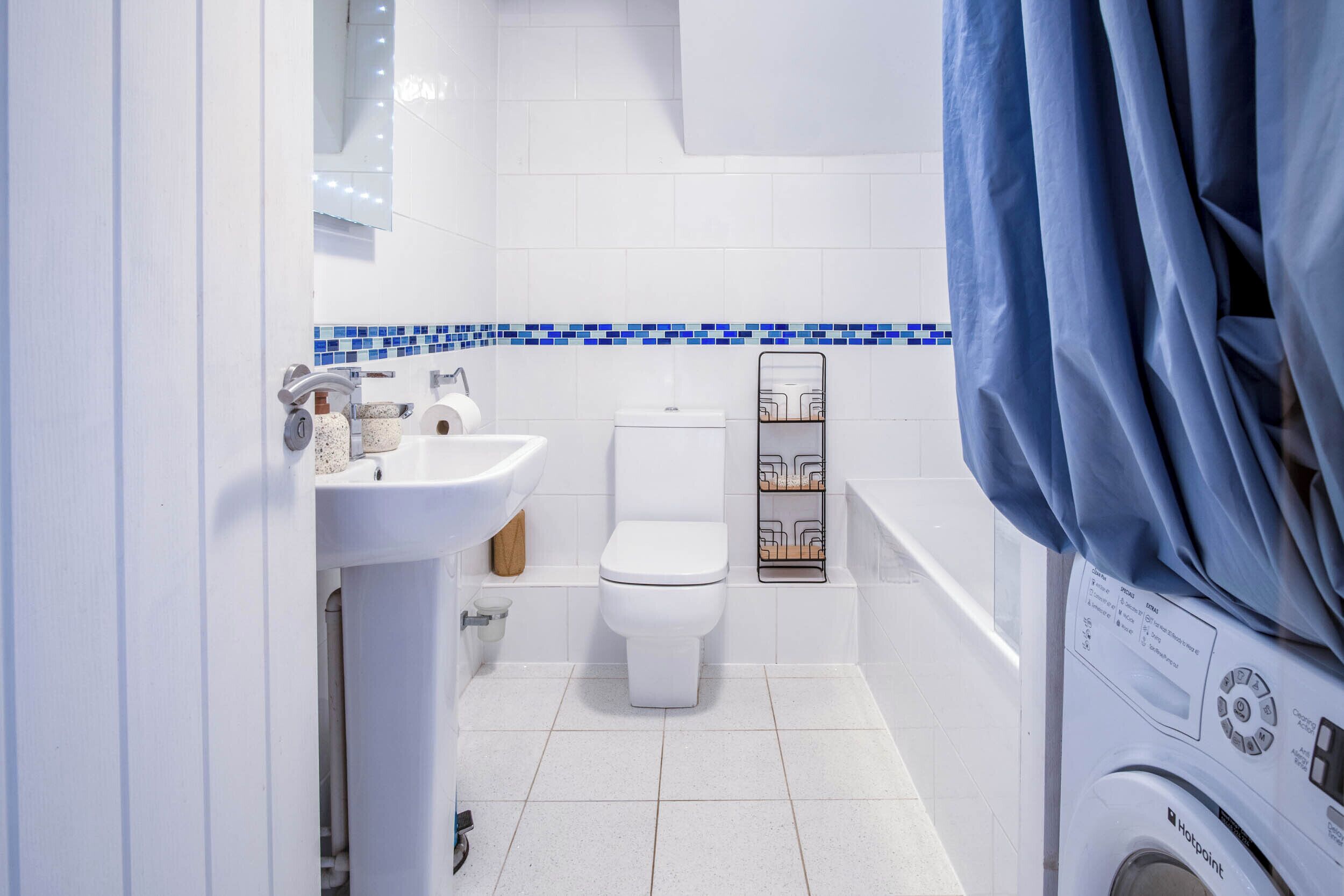 Une petite salle de bain comprenant des toilettes, un lavabo et un lave-linge.