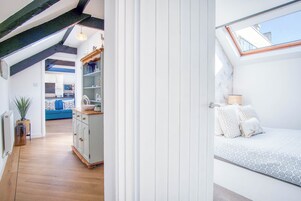 Ein Schlafzimmer mit Dachfenster, einem Bett mit weißer Bettwäsche und Blick auf den Himmel.