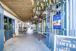 Ein Straßencafé mit hängenden Pflanzen, Tischen und Stühlen.