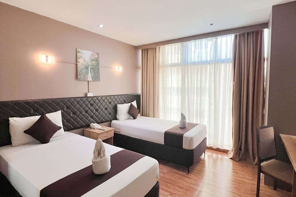 Une chambre d’hôtel avec deux lits, un bureau et une chaise.