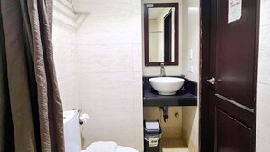 A bathroom with a toilet, sink, mirror, and a door with a 'No Smoking' sign. - Cebu Capitol Central Hotel & Suites powered by Cocotel (Cebu City)