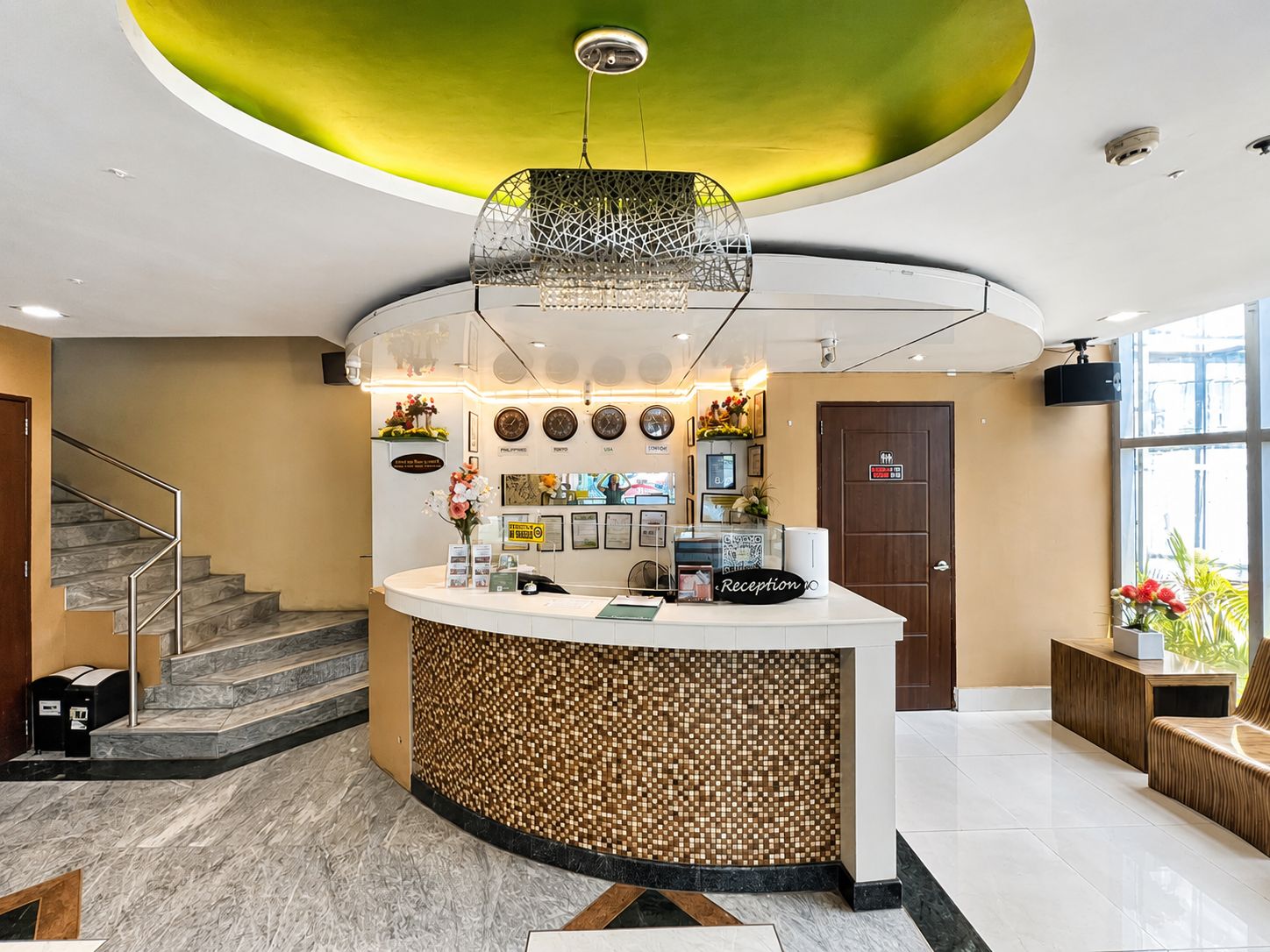 A reception area with a curved counter, a staircase, and a clock on the wall.