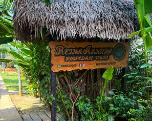 A wooden sign with the text 'REINA ARRERA HOSPEDADE-TOURS' and a contact number.