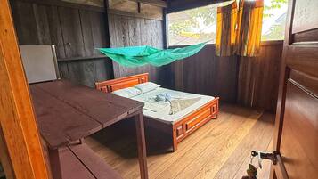 A wooden interior with a bed, a table, and a ceiling fan.