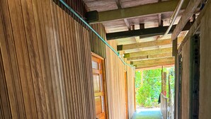 A wooden corridor with a door leading to an outdoor area. - Authentic Amazon | Indigenous Lodging and Jungle Tours (Loreto Mocagua)