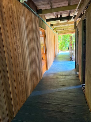 A wooden corridor with a door leading to an outdoor area. - Authentic Amazon | Indigenous Lodging and Jungle Tours (Loreto Mocagua)