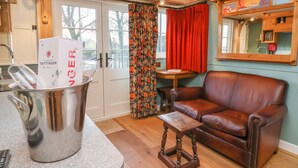 A cozy living room with a brown leather sofa, a small wooden table, and a metal container with a box labeled "Taittinger". - Arts and Crafts (York)