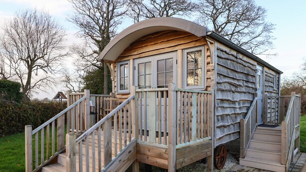 A wooden playhouse with a curved roof, a set of stairs, and a small porch area. - Arts and Crafts (York)