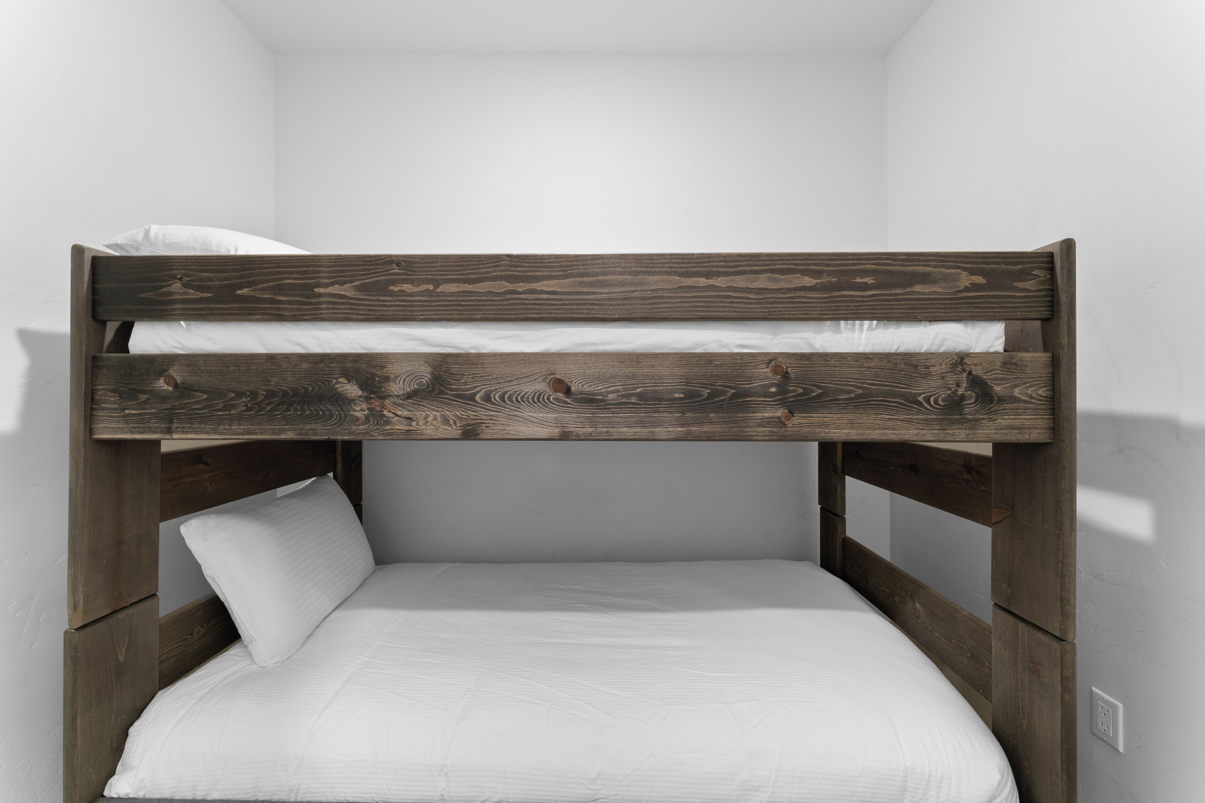 Un letto a castello con struttura in legno e biancheria bianca.