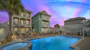 Ein Hotel mit Schwimmbad, Liegestühlen und einem Sonnenuntergangshimmel.