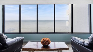 A room with a large window, a wooden coffee table, and two leather sofas. - Bayside Sandestin studio @ Links golf & conference center (Miramar Beach)