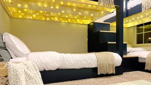 Quarto moderno com cama, um pequeno espaço para sentar e teto com luzes de fada.