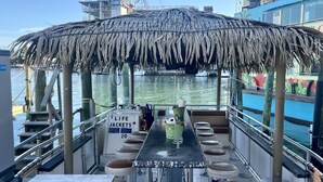 A bar area with a thatched roof, stools, and a sign for life jackets. - Clearwater Beach, Your Dream Vacation, Condo (Clearwater)