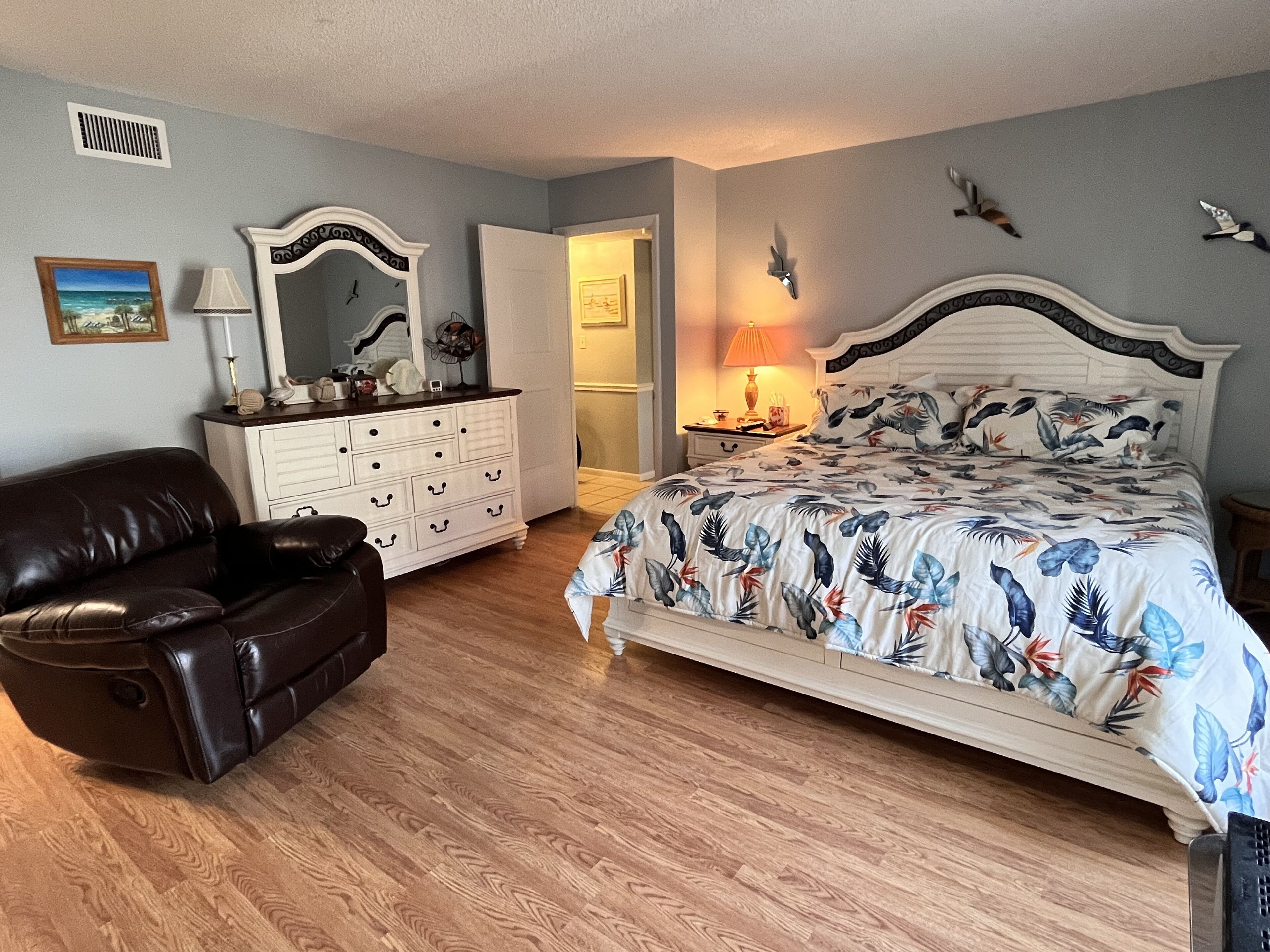 Un dormitorio con cama, cómoda, silla y mesita de noche.